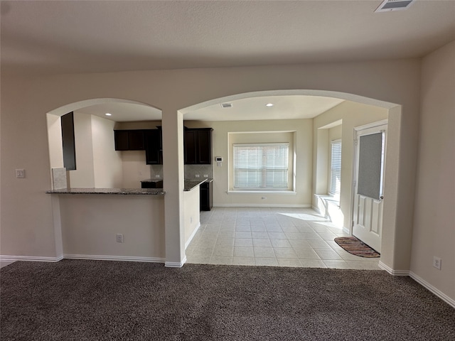 kitchen featuring light stone countertops, light colored carpet, and kitchen peninsula