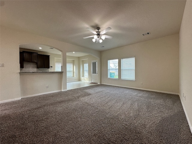 unfurnished living room featuring carpet flooring, ceiling fan, and a textured ceiling