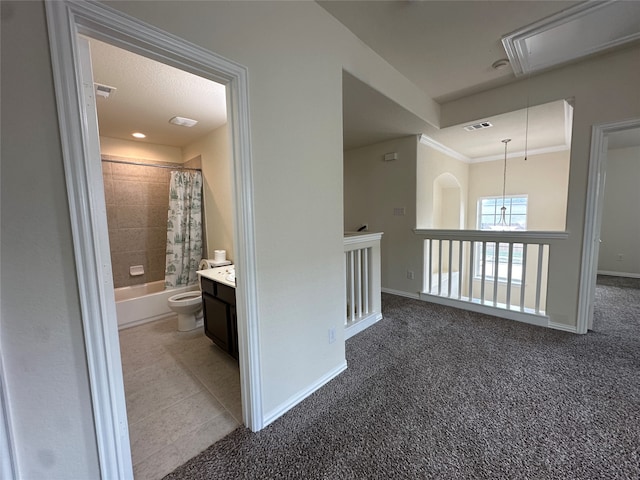 hall with dark colored carpet and ornamental molding