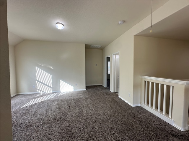 carpeted empty room with a textured ceiling and lofted ceiling