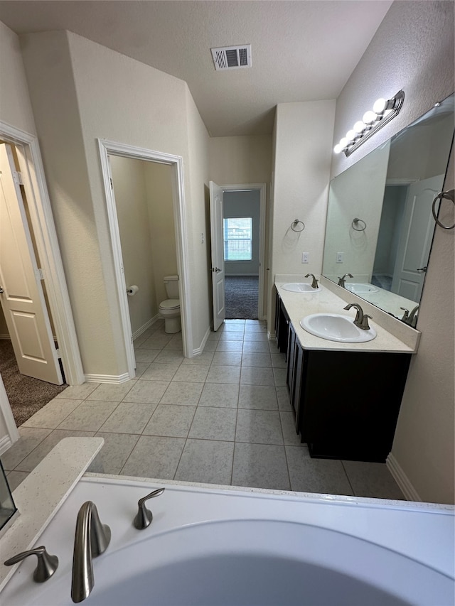 bathroom with tile patterned floors, vanity, a bathtub, and toilet