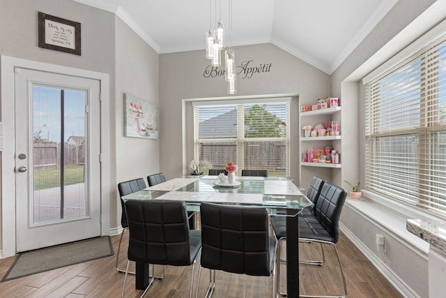 dining room featuring dark hardwood / wood-style flooring, lofted ceiling, and ornamental molding