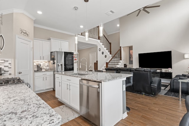 kitchen with white cabinets, appliances with stainless steel finishes, a center island with sink, and ceiling fan