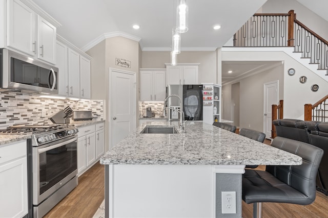 kitchen with decorative backsplash, a kitchen bar, stainless steel appliances, and a kitchen island with sink