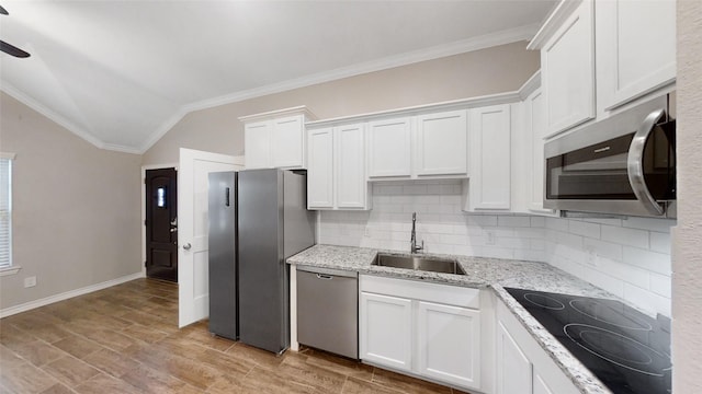 kitchen with sink, white cabinets, stainless steel appliances, and vaulted ceiling