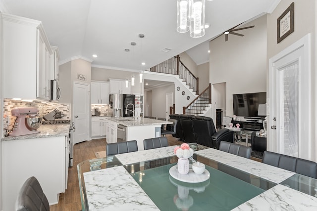 dining space featuring ceiling fan, sink, light hardwood / wood-style floors, vaulted ceiling, and ornamental molding