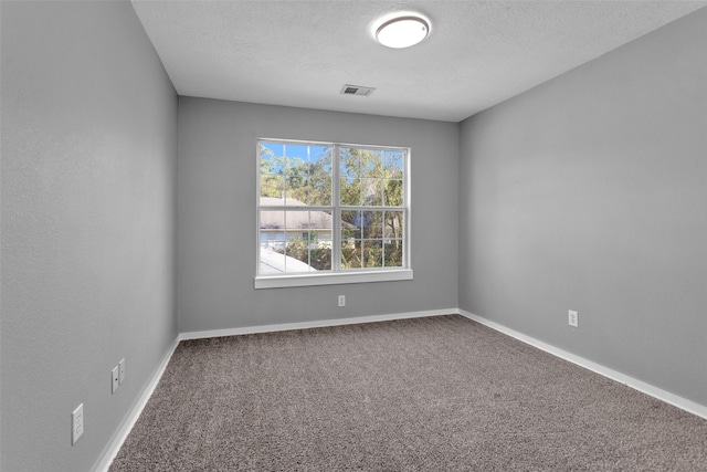 carpeted empty room featuring a textured ceiling