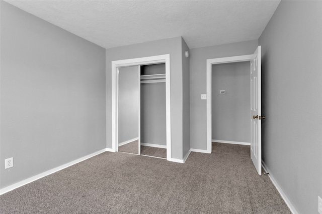 unfurnished bedroom featuring dark carpet, a textured ceiling, and a closet