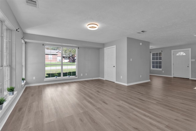 unfurnished living room featuring wood-type flooring and a textured ceiling