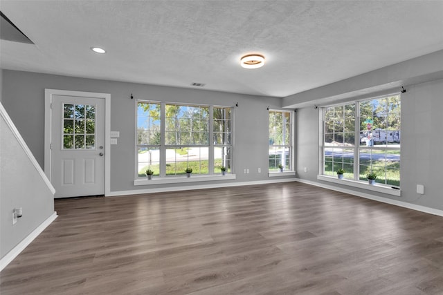 unfurnished living room with dark hardwood / wood-style flooring and a textured ceiling