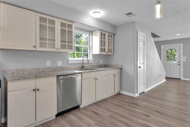 kitchen with light stone countertops, light wood-type flooring, stainless steel dishwasher, a textured ceiling, and sink