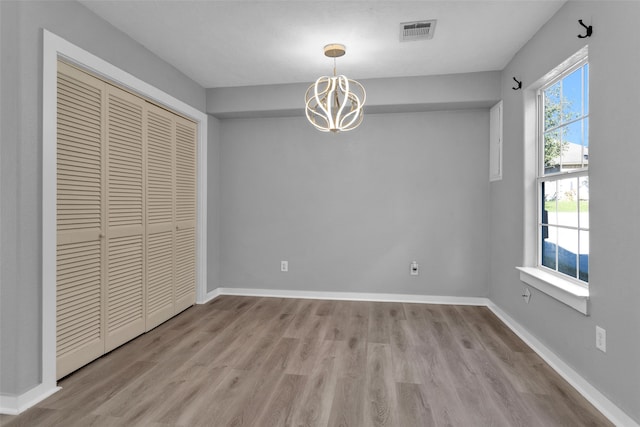 unfurnished dining area featuring light hardwood / wood-style floors and an inviting chandelier