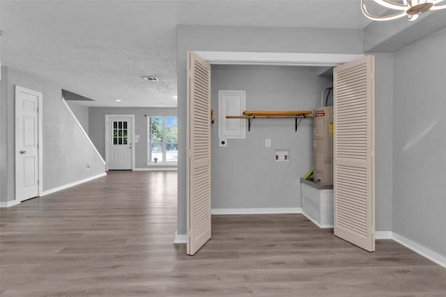 clothes washing area featuring electric dryer hookup, water heater, washer hookup, and light hardwood / wood-style floors