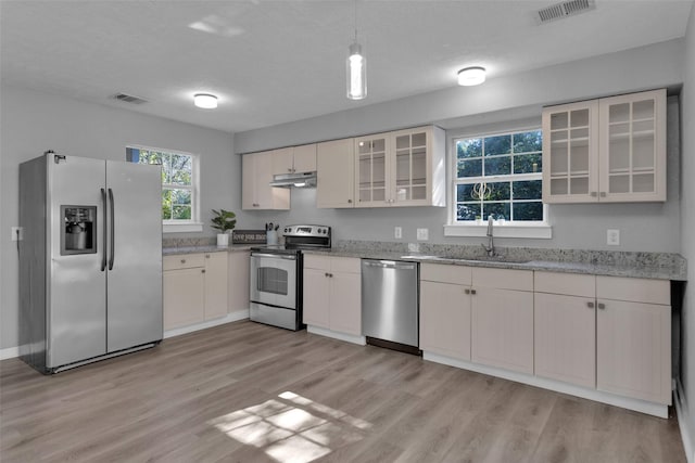 509 Spruce Dr, Conroe, TX 77302 - kitchen with appliances with stainless steel finishes, a sink, under cabinet range hood, and light wood-type flooring