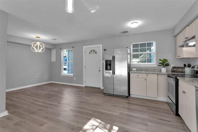 509 Spruce Dr, Conroe, TX 77302 - kitchen featuring appliances with stainless steel finishes, under cabinet range hood, a chandelier, light wood-style floors, and baseboards