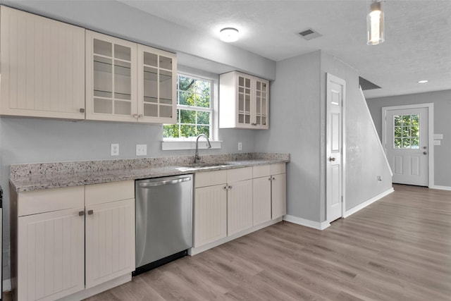 509 Spruce Dr, Conroe, TX 77302 - kitchen featuring stainless steel dishwasher, a sink, light wood finished floors, baseboards, and light stone countertops