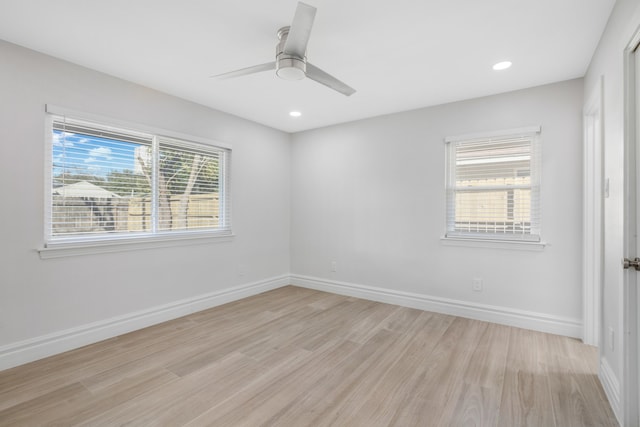 spare room featuring ceiling fan, light wood-type flooring, and a wealth of natural light