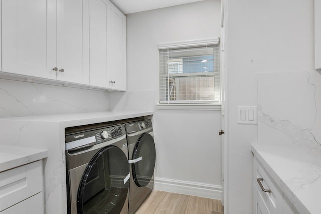 laundry room with cabinets, light wood-type flooring, and washing machine and clothes dryer