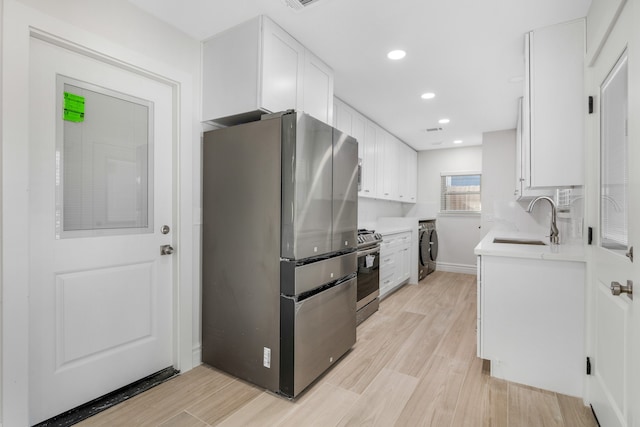 kitchen featuring white cabinets, light wood-type flooring, stainless steel appliances, and sink