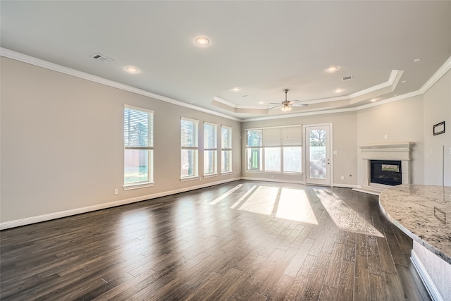 unfurnished living room featuring dark hardwood / wood-style floors, ceiling fan, a raised ceiling, and crown molding