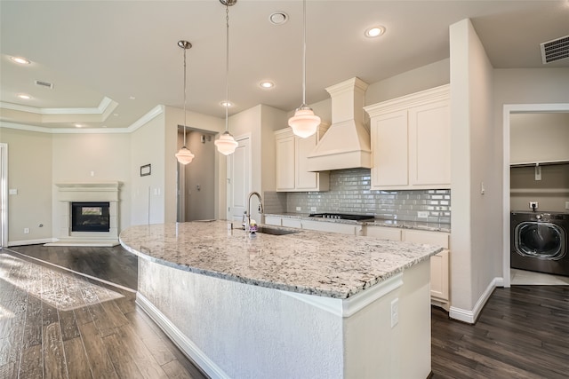 kitchen with custom range hood, decorative light fixtures, washer / dryer, dark hardwood / wood-style floors, and white cabinetry