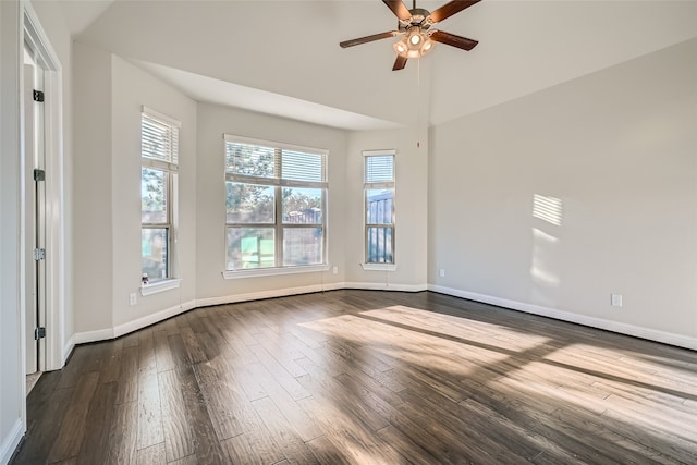 spare room featuring ceiling fan, a towering ceiling, and dark wood-type flooring