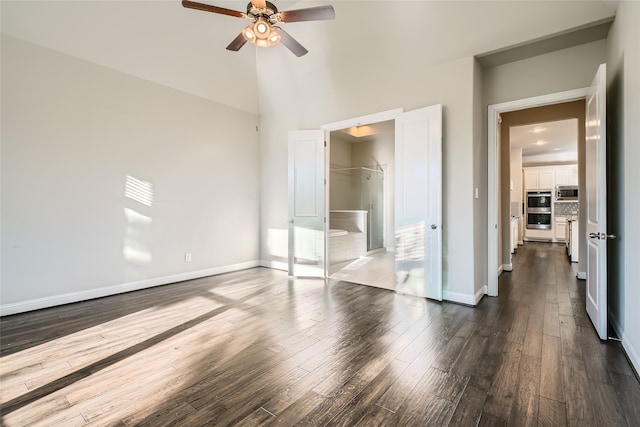 unfurnished bedroom featuring a walk in closet, dark hardwood / wood-style flooring, ceiling fan, and lofted ceiling