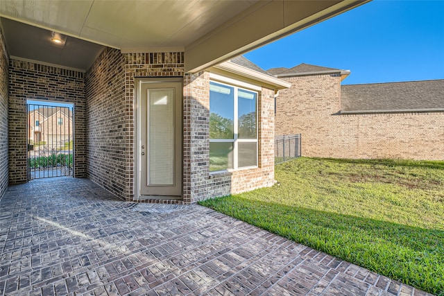 view of exterior entry featuring a lawn and a patio