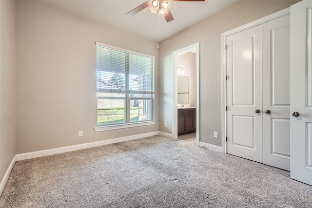 unfurnished bedroom with light carpet, a closet, ensuite bath, and ceiling fan