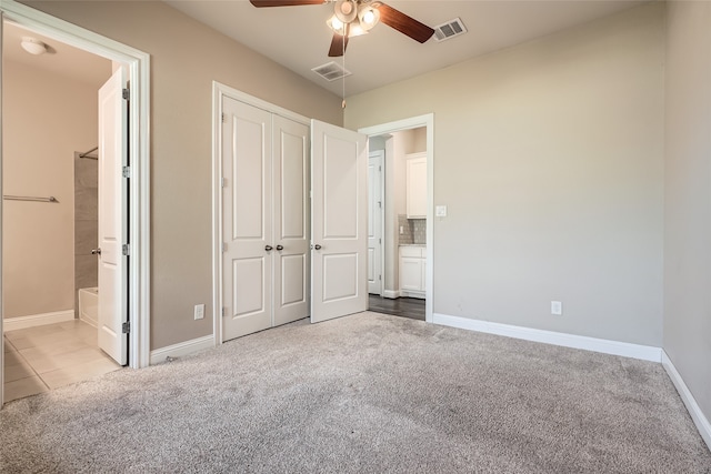 unfurnished bedroom with a closet, connected bathroom, light colored carpet, and ceiling fan