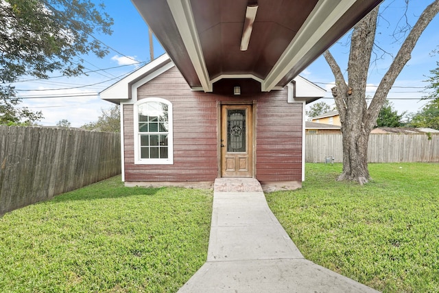 view of exterior entry with a yard