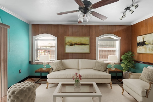 sitting room featuring wooden walls, track lighting, ceiling fan, and crown molding