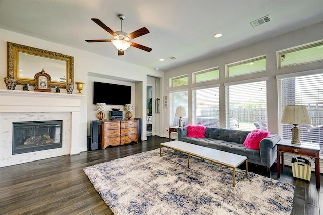 living room featuring a high end fireplace, dark hardwood / wood-style floors, and ceiling fan