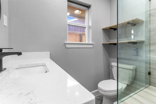 bathroom featuring vanity, toilet, and a shower with shower door