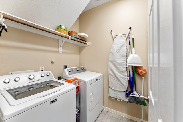 clothes washing area featuring light tile patterned floors, a textured ceiling, laundry area, independent washer and dryer, and baseboards