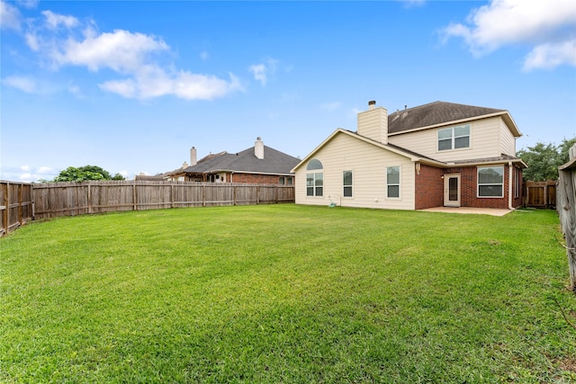 rear view of house featuring a patio area, brick siding, a lawn, and a fenced backyard