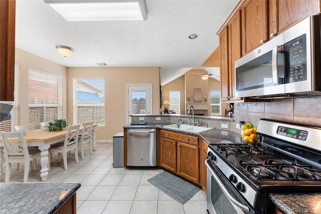 kitchen featuring brown cabinets, light tile patterned floors, tasteful backsplash, appliances with stainless steel finishes, and a sink