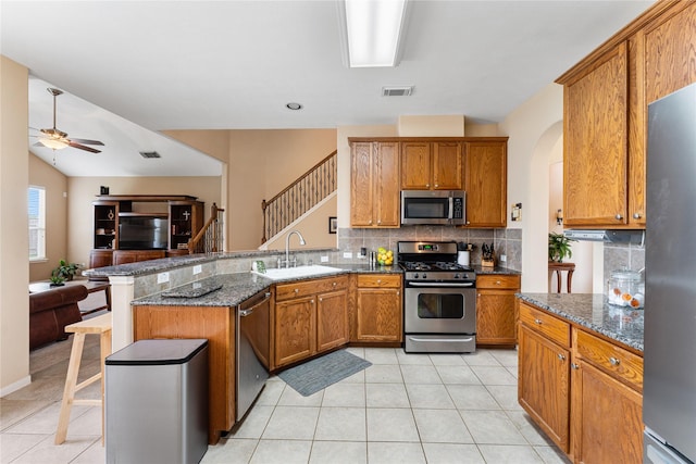 kitchen with visible vents, appliances with stainless steel finishes, brown cabinets, a peninsula, and a sink