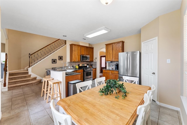 dining room with arched walkways, visible vents, stairway, light tile patterned flooring, and baseboards