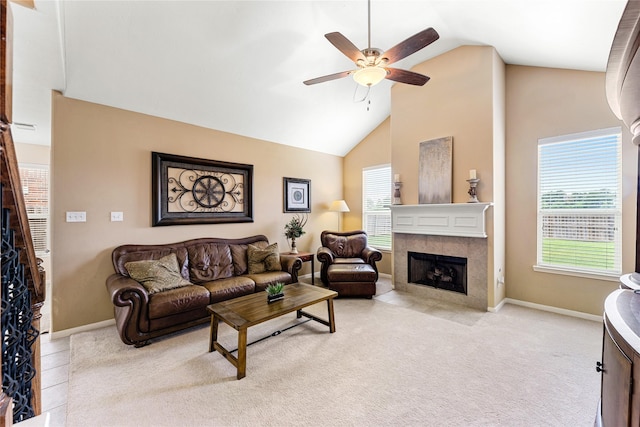 living area with high vaulted ceiling, light carpet, a ceiling fan, baseboards, and a tiled fireplace