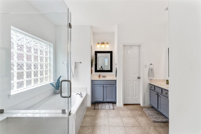 full bathroom featuring a bath, two vanities, a sink, and tile patterned floors