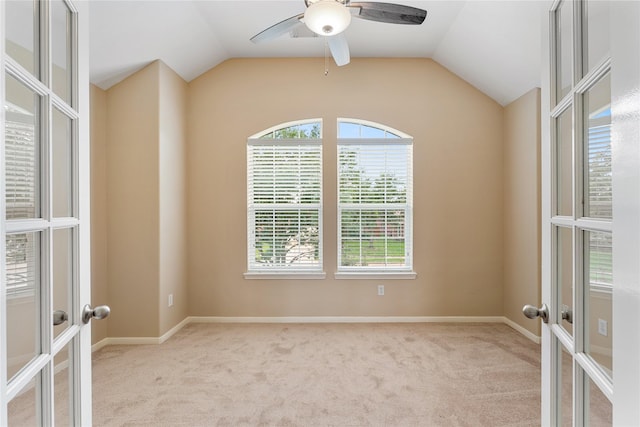 carpeted spare room featuring lofted ceiling, ceiling fan, baseboards, and french doors