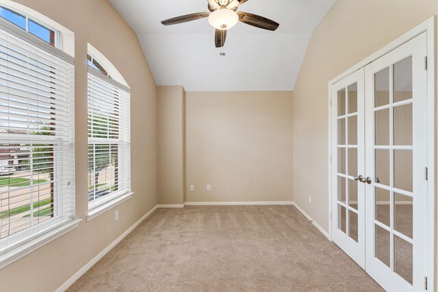 carpeted empty room featuring lofted ceiling, baseboards, a ceiling fan, and french doors