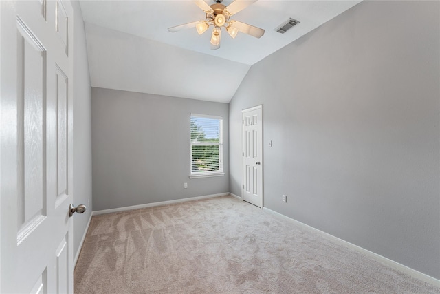 carpeted empty room featuring vaulted ceiling, ceiling fan, visible vents, and baseboards