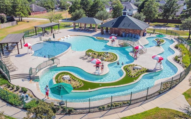 pool featuring fence, a water play area, a water slide, and a gazebo