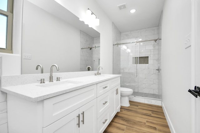 bathroom featuring vanity, wood-type flooring, a shower with shower door, and toilet