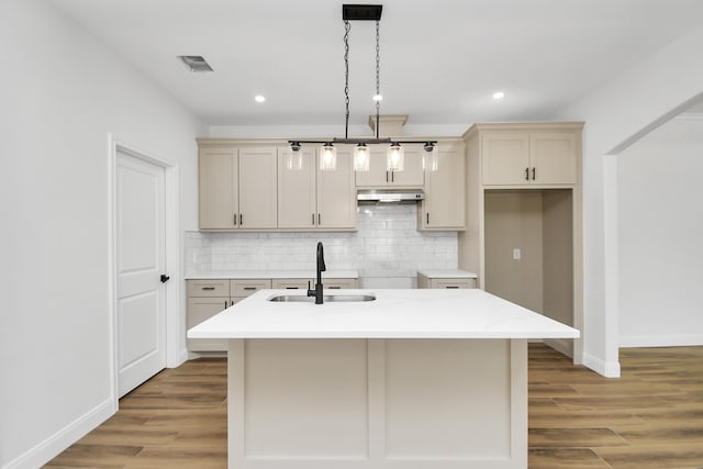 kitchen featuring a center island with sink, wood-type flooring, sink, and cream cabinets