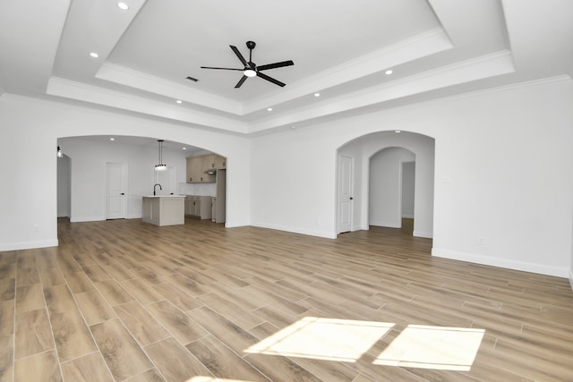 unfurnished living room featuring light wood-type flooring and a raised ceiling