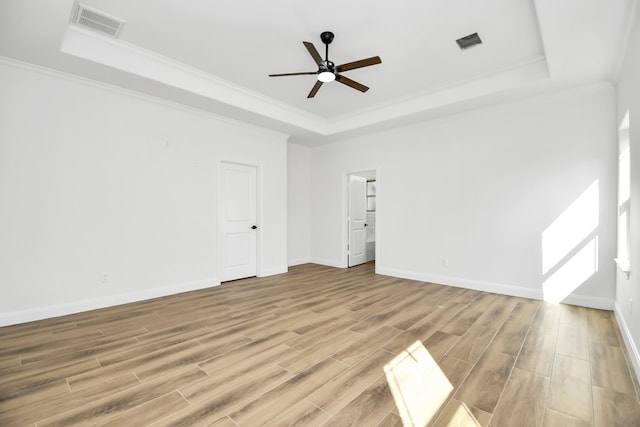 empty room featuring a tray ceiling, light hardwood / wood-style flooring, ceiling fan, and ornamental molding