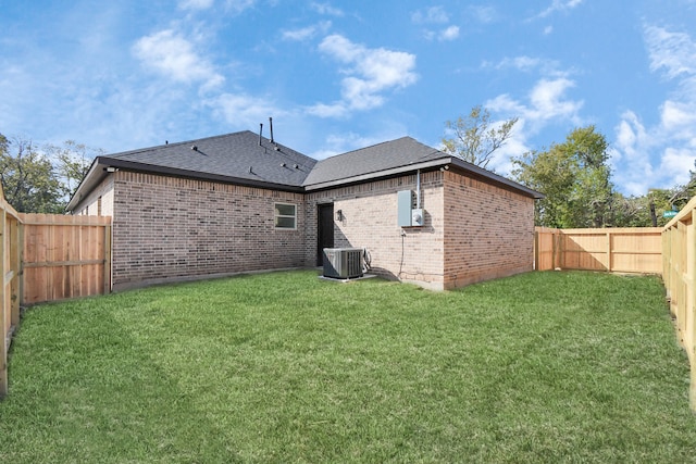 back of property with central AC and a lawn